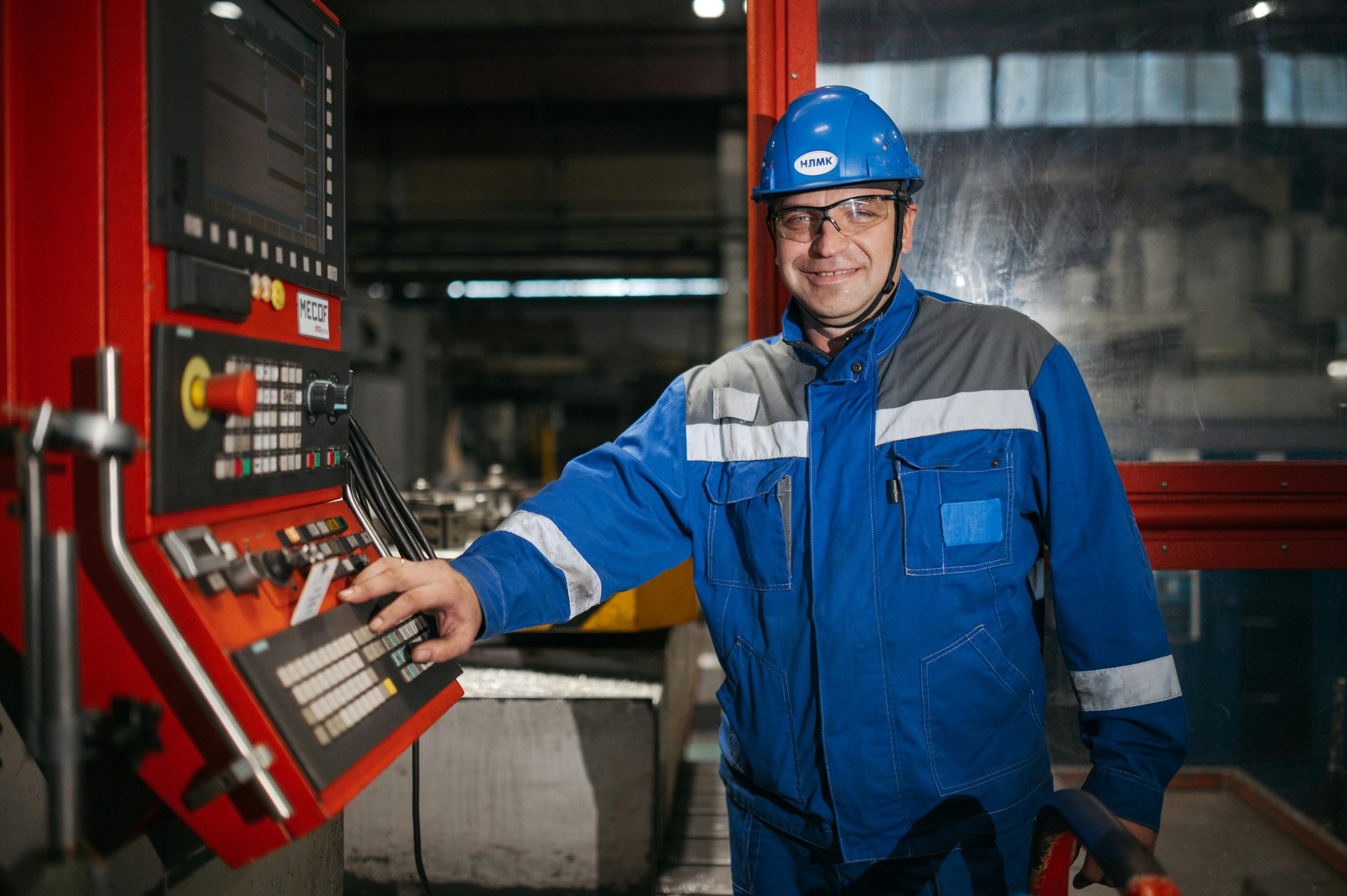 আমাদের সম্পর্কে Man in safety gear works at CNC machine in a Russian factory.